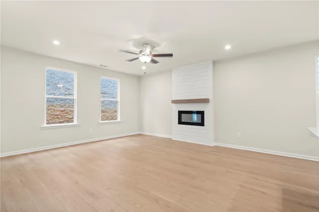 an empty room with windows and ceiling fan