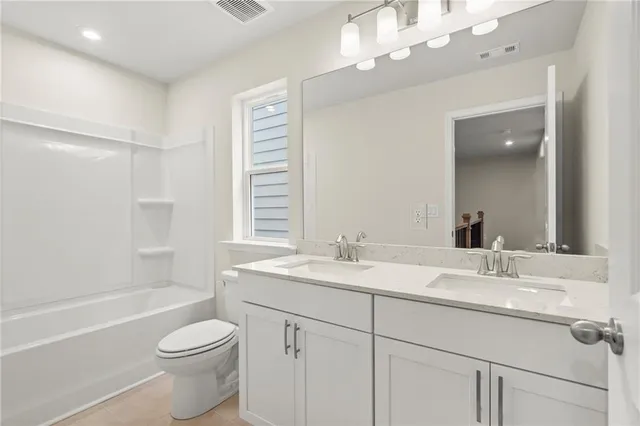 a bathroom with a toilet a sink a tub and a mirror