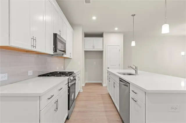 a kitchen with stainless steel appliances granite countertop a sink a stove and a refrigerator