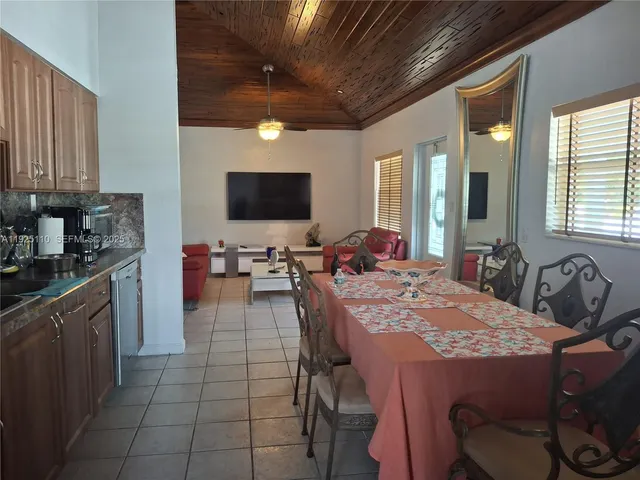 a kitchen with stainless steel appliances kitchen island granite countertop a table chairs in it and a window