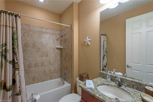 a bathroom with a granite countertop tub a sink and a large mirror