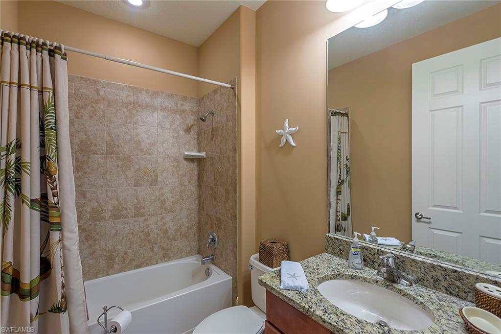 9102 Capistrano Street South, Unit 723 Naples, FL 34113 - Photo 11 of 12 a bathroom with a granite countertop tub a sink and a large mirror