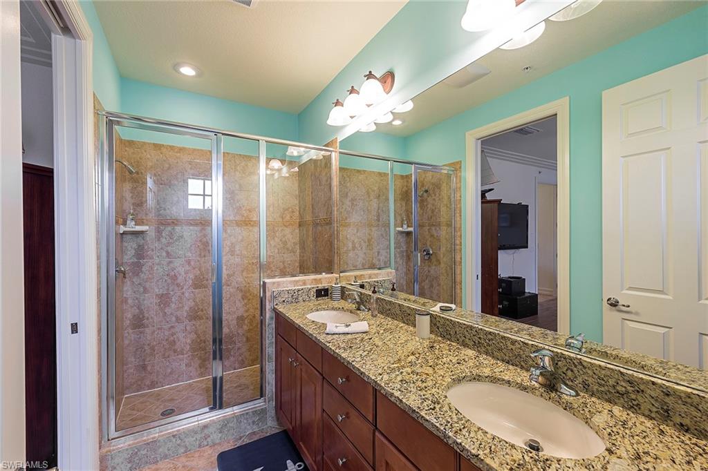 9102 Capistrano Street South, Unit 723 Naples, FL 34113 - Photo 9 of 12 a bathroom with a granite countertop double vanity sink mirror and shower