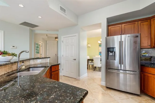 a kitchen with granite countertop a refrigerator a sink a stove and cabinets