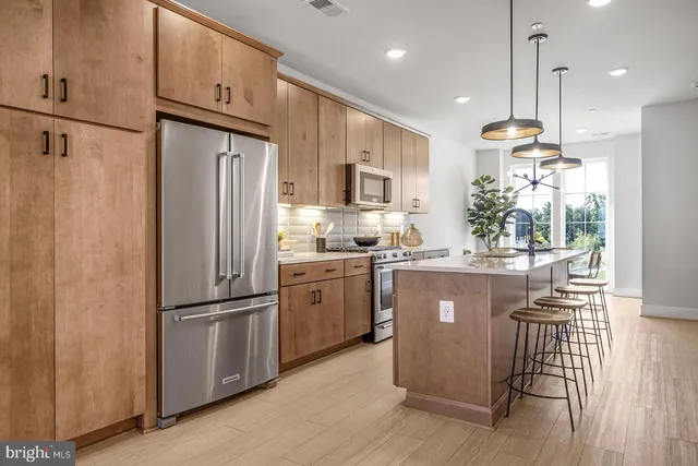 a kitchen with kitchen island granite countertop a refrigerator a sink dishwasher a stove and white cabinets with wooden floor