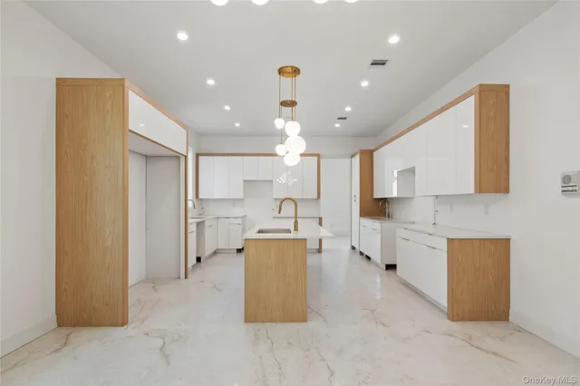 a large kitchen with kitchen island white cabinets and stainless steel appliances