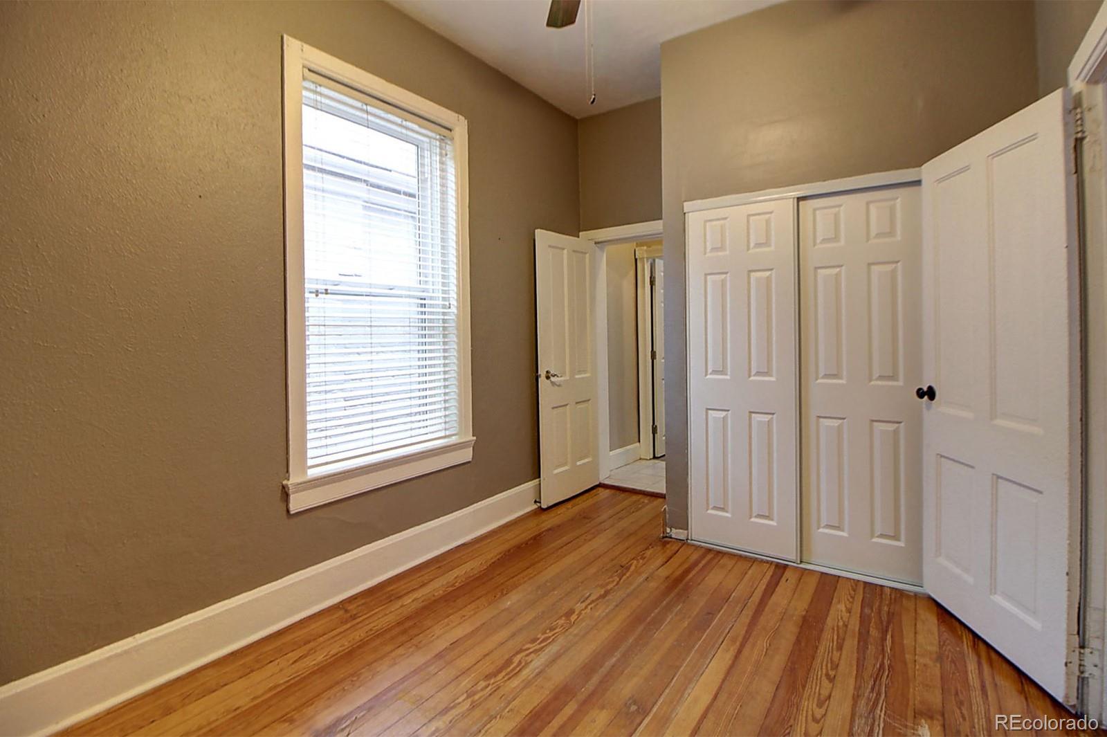 328 Inca Street Denver, CO 80223 - Photo 12 of 35 a view of an empty room with wooden floor and a window