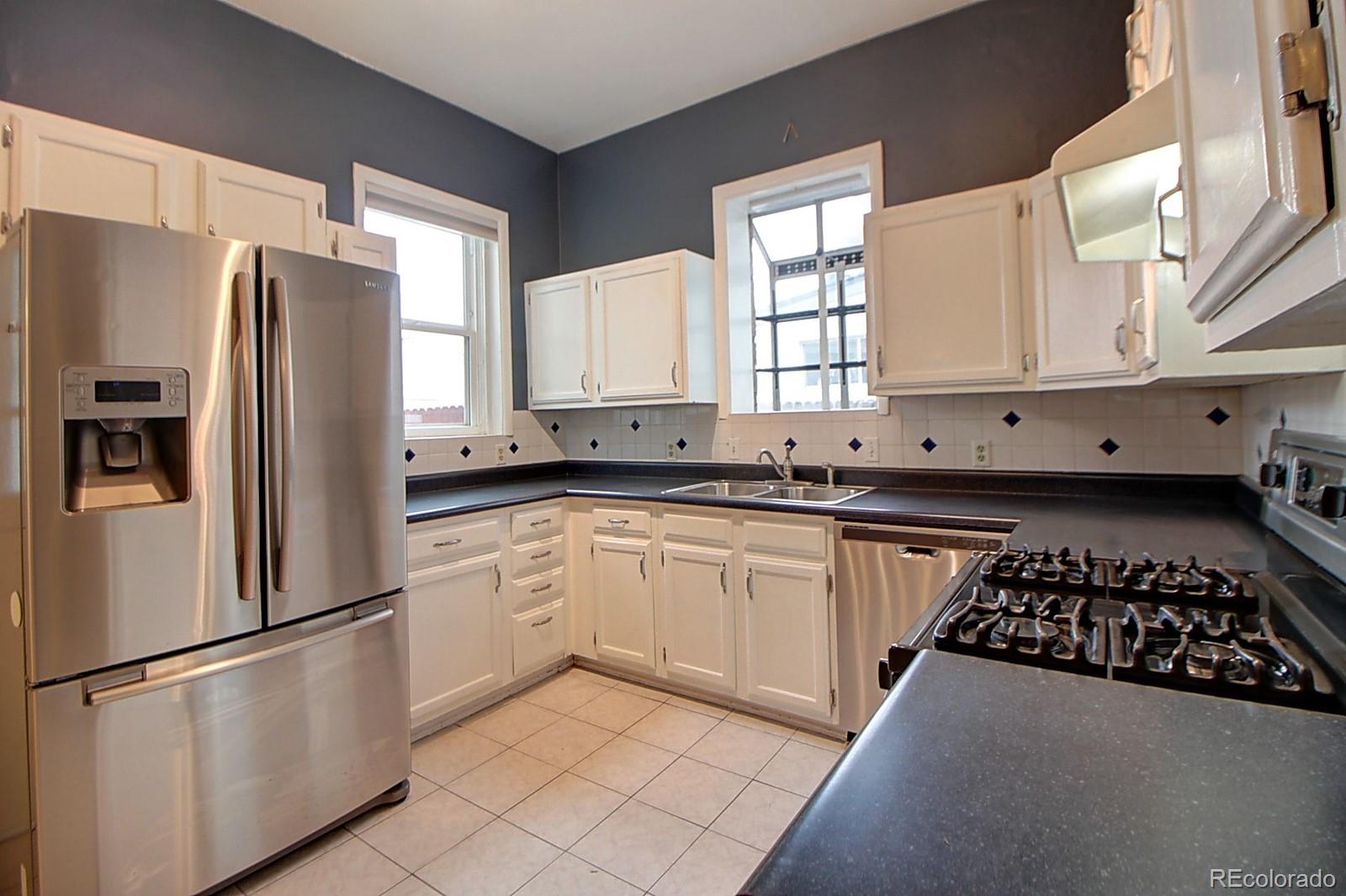 328 Inca Street Denver, CO 80223 - Photo 21 of 35 a kitchen with a refrigerator a sink a window and cabinets