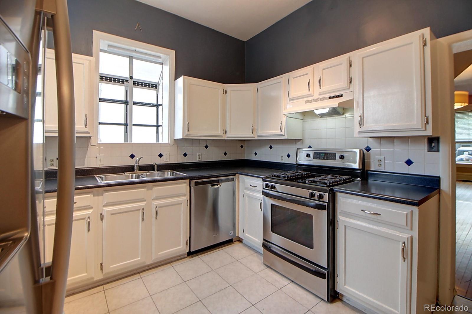328 Inca Street Denver, CO 80223 - Photo 22 of 35 a kitchen with granite countertop white cabinets sink and stainless steel appliances