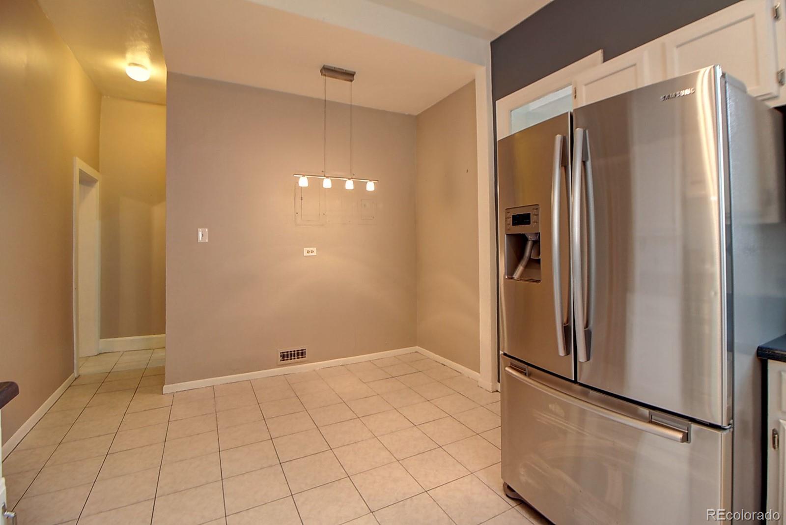 328 Inca Street Denver, CO 80223 - Photo 23 of 35 a view of a refrigerator in kitchen and an empty room in wooden floor