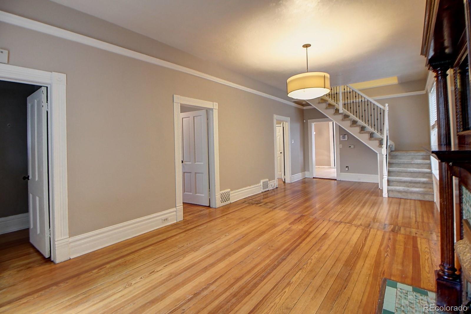 328 Inca Street Denver, CO 80223 - Photo 4 of 35 a view of empty room with wooden floor and fireplace