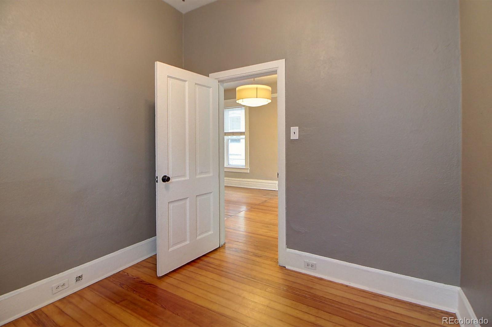 328 Inca Street Denver, CO 80223 - Photo 10 of 35 a view of an empty room with wooden floor and a window