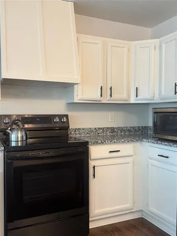 a kitchen with granite countertop white cabinets and stainless steel appliances