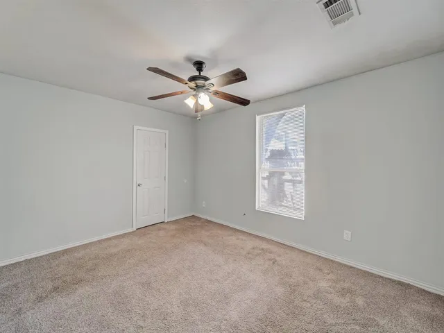an empty room with windows and fan