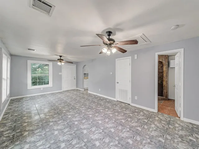 an empty room with windows and fan