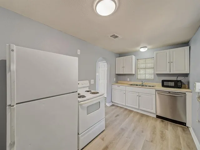 a kitchen with white cabinets and white appliances