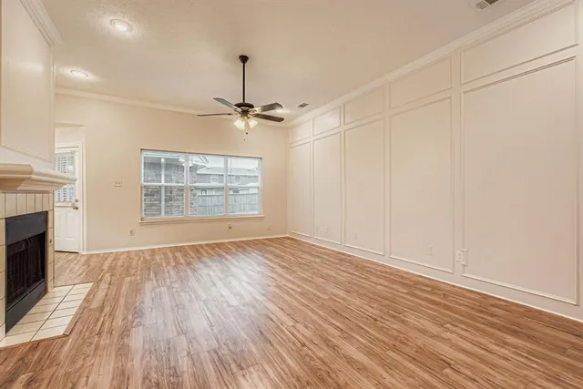 an empty room with wooden floor fireplace and windows