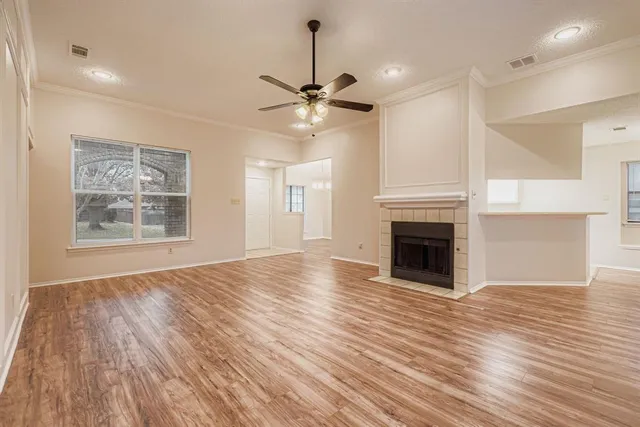 a view of an empty room with wooden floor fireplace and a window