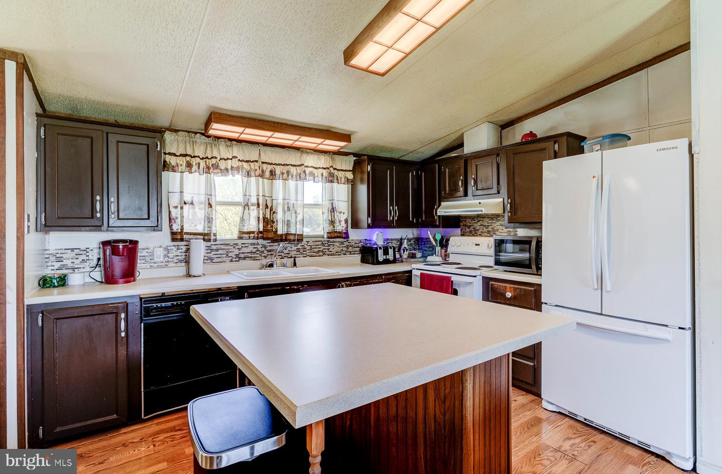 936 Newark Road Avondale, PA 19311 - Photo 5 of 38 a kitchen with granite countertop a refrigerator a sink dishwasher a stove and a refrigerator with wooden floor