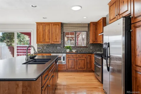 a kitchen with stainless steel appliances granite countertop wooden cabinets a sink dishwasher a stove and a refrigerator