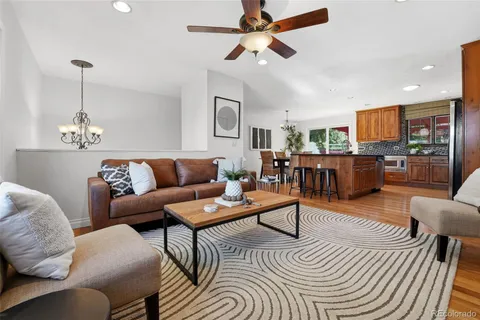 a living room with furniture kitchen view and a wooden floor