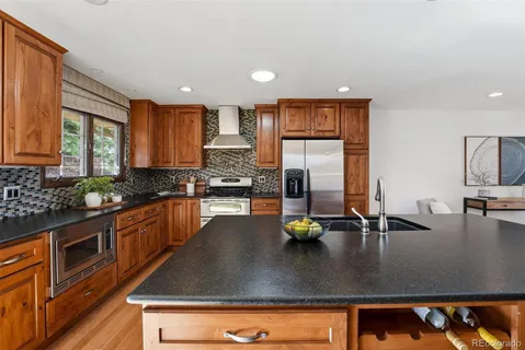 a kitchen with stainless steel appliances granite countertop a sink a stove and refrigerator