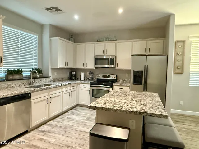 a kitchen with kitchen island granite countertop white cabinets and refrigerator