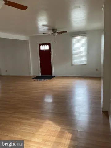 an empty room with wooden floor closet and windows