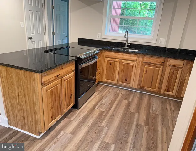 a kitchen with granite countertop wooden cabinets a sink and a window