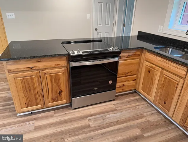 a kitchen with granite countertop a stove top oven and cabinets