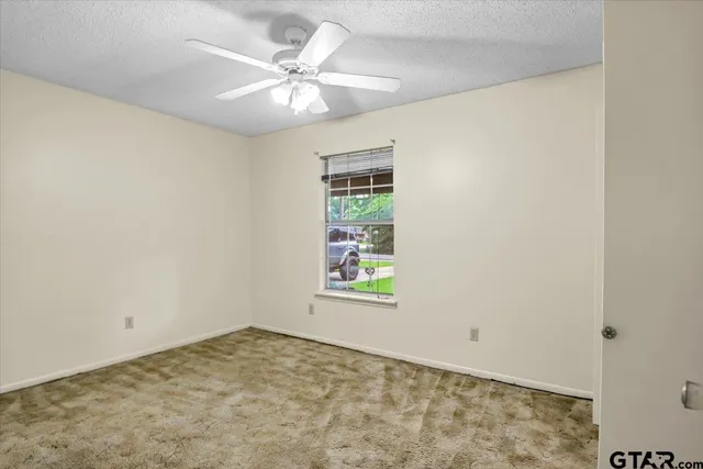 an empty room with windows and fan