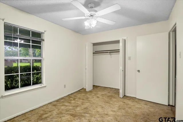 an empty room with closet and a chandelier fan