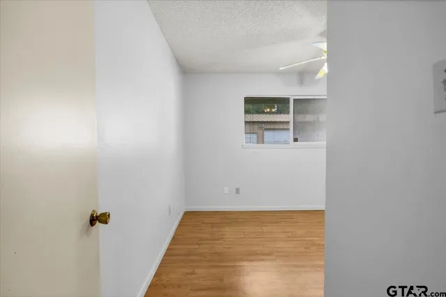 an empty room with a window and a ceiling fan