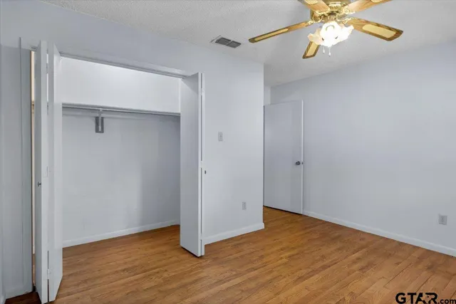 an empty room with wooden floor mirror and windows