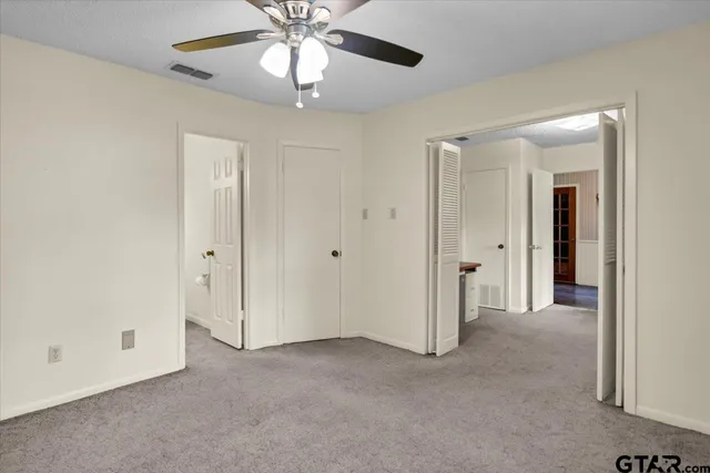 an empty room with a chandelier fan and closet area