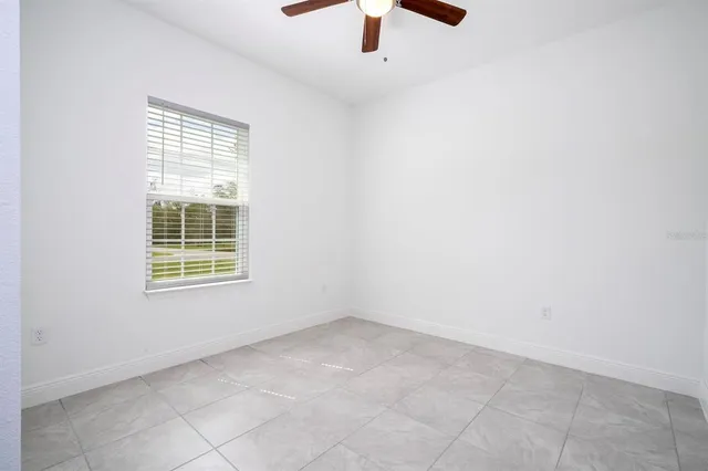 an empty room with a ceiling fan and a window