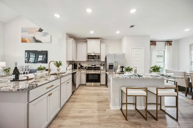 a large kitchen with kitchen island white cabinets and stainless steel appliances