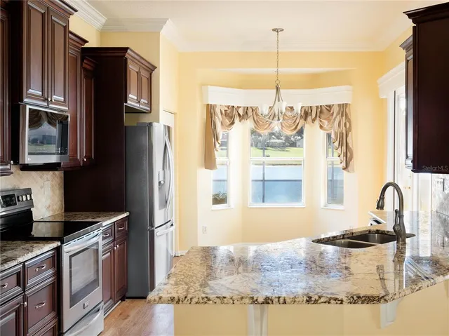 a kitchen with granite countertop a refrigerator stove and sink