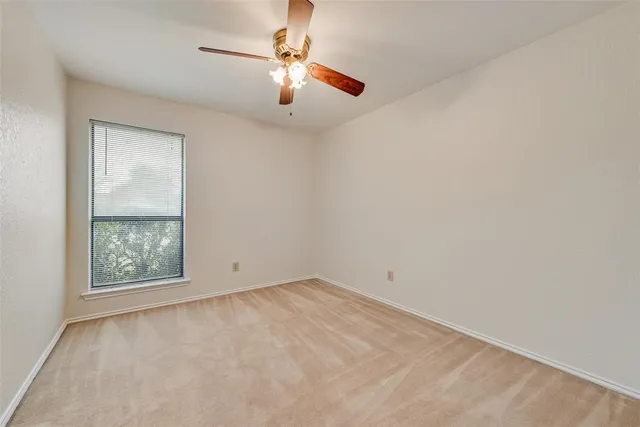 an empty room with a chandelier fan and windows