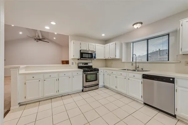 a kitchen with a sink a stove top oven and white cabinets