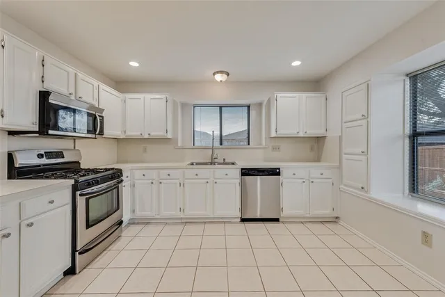 a kitchen with a sink a stove top oven and white cabinets