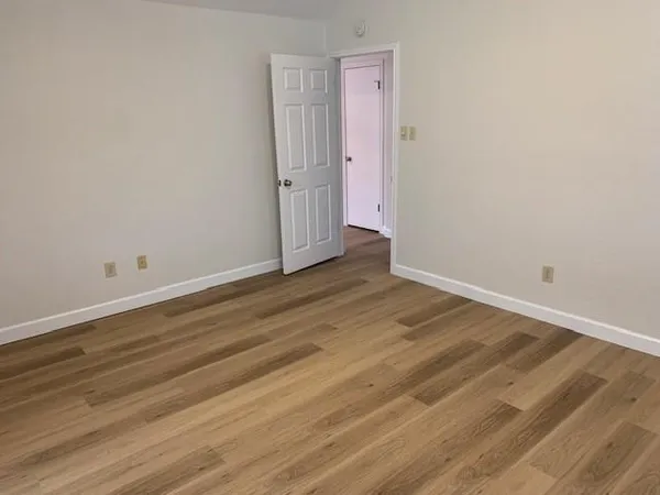 an empty room with wooden floor cabinet and windows