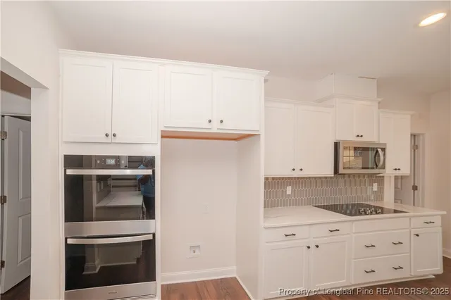 a kitchen with granite countertop white cabinets and white appliances
