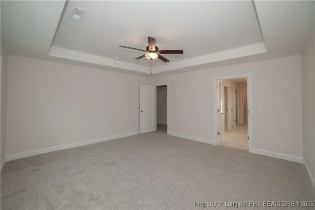 an empty room with a ceiling fan and carpet