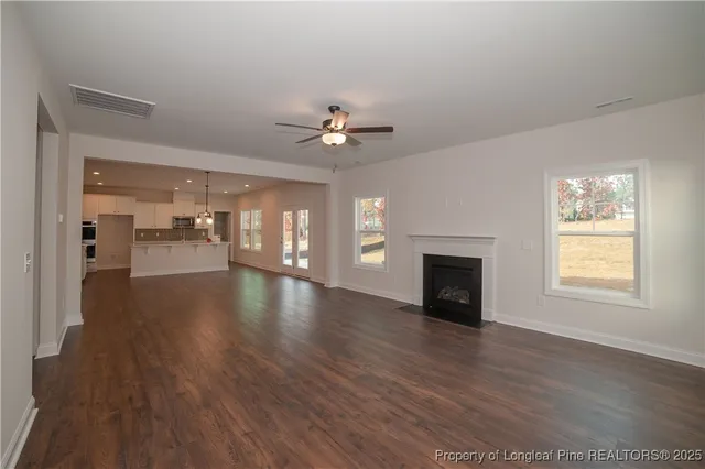 wooden floor in an empty room with a fireplace and a window