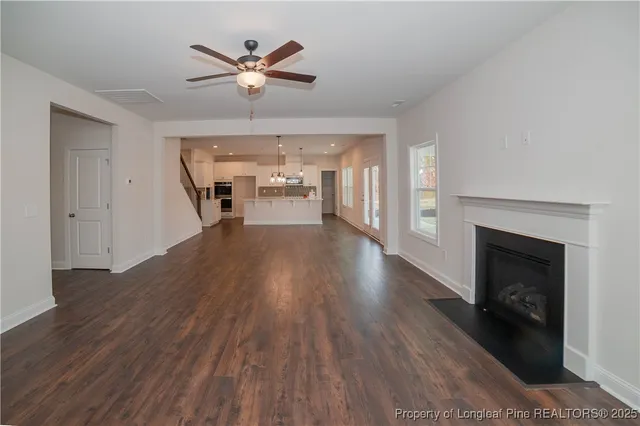 a view of a livingroom with a fireplace a ceiling fan and wooden floor