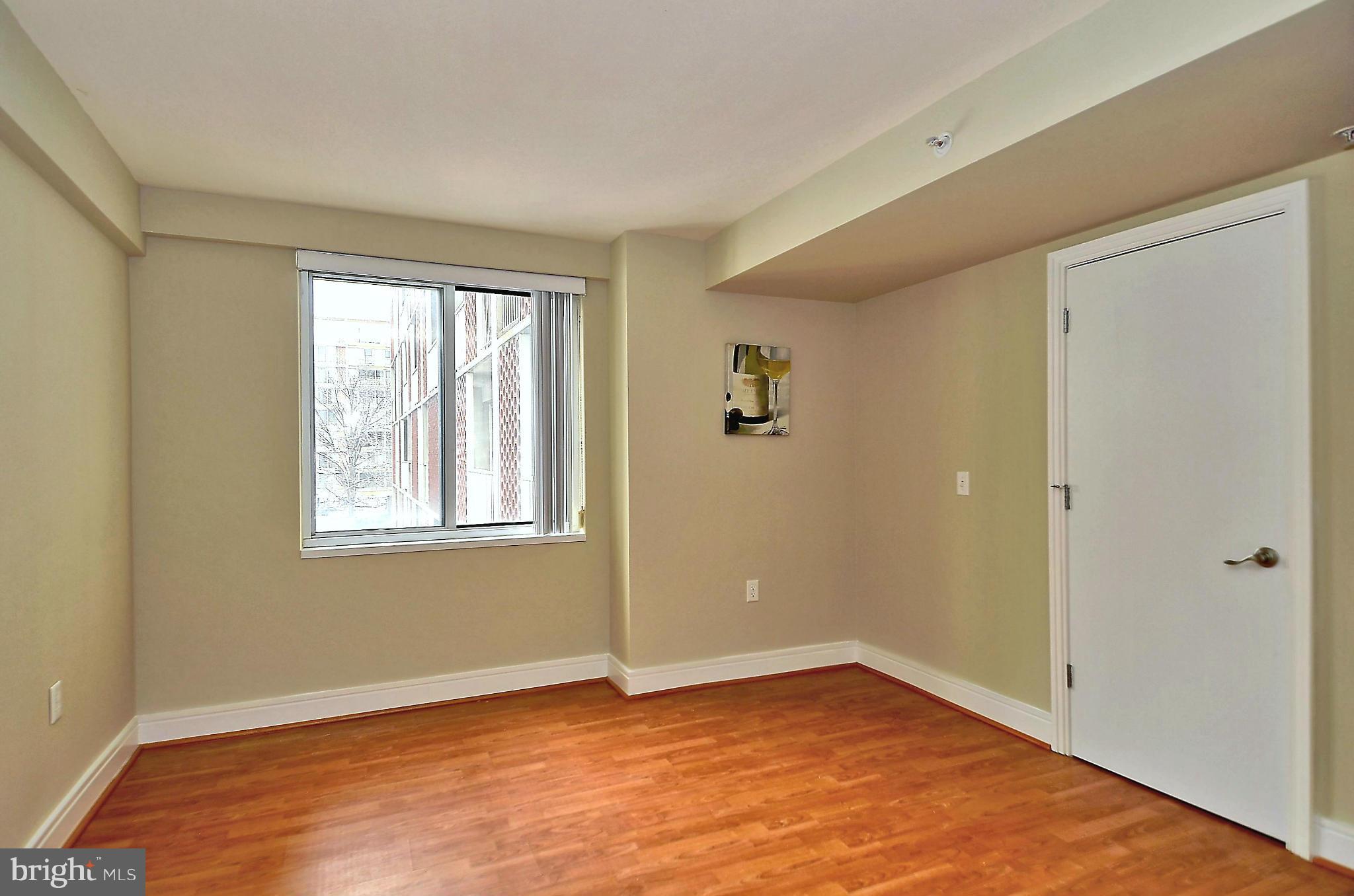 800 4th Street Southwest, Unit N201 Washington, DC 20024 - Photo 5 of 25 a view of an empty room with wooden floor and a window