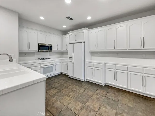 a kitchen with white cabinets and white appliances