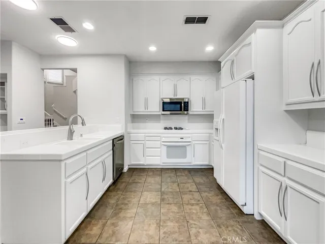 a kitchen with white cabinets and white appliances
