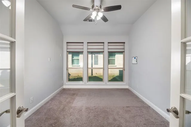 a view of an empty room with chandelier fan and fire place